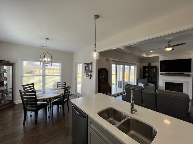 kitchen featuring a sink, dark wood-style floors, light countertops, dishwasher, and hanging light fixtures