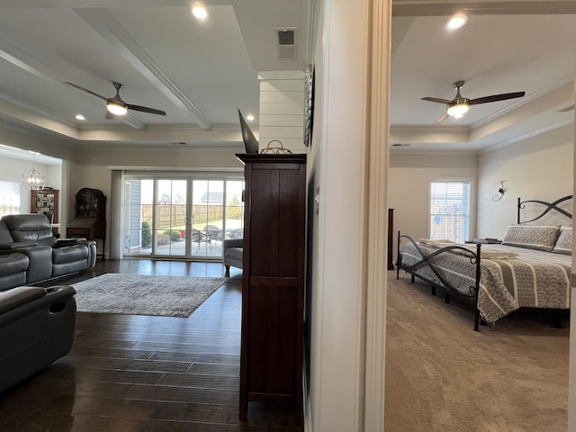 bedroom featuring a tray ceiling, multiple windows, visible vents, and ornamental molding