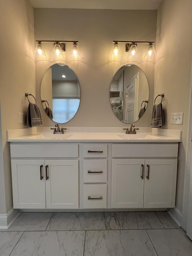 bathroom featuring double vanity, baseboards, marble finish floor, and a sink