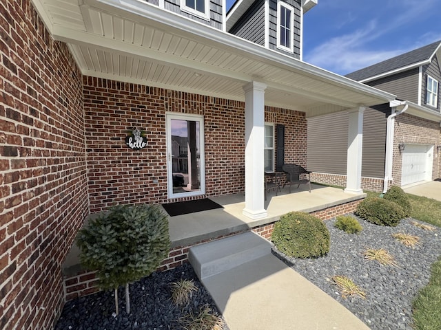 entrance to property with brick siding, covered porch, and a garage