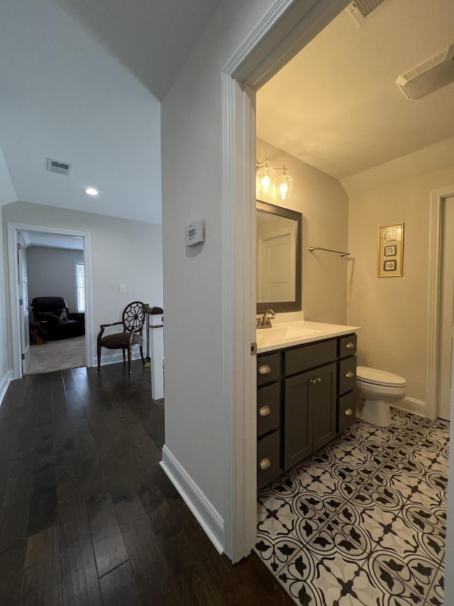 bathroom with vanity, toilet, baseboards, and visible vents