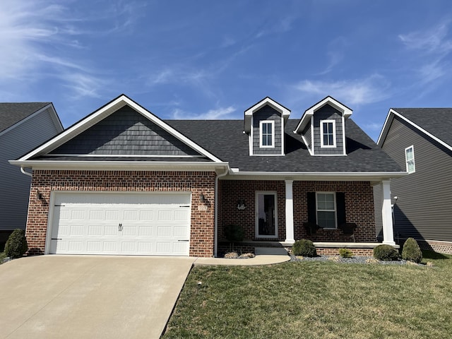 view of front of property with brick siding, a front lawn, a porch, a garage, and driveway