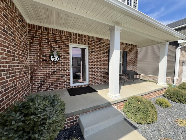 doorway to property featuring brick siding and covered porch