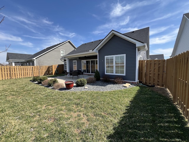 rear view of property featuring a fenced backyard, a lawn, a shingled roof, and a patio