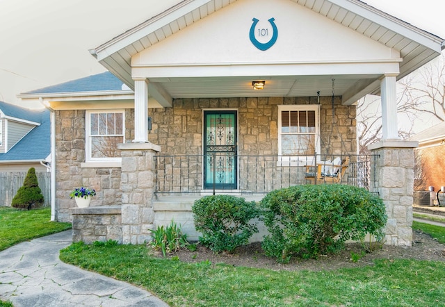 view of front of property with a porch, stone siding, and a shingled roof