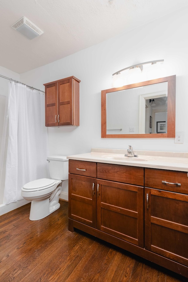 full bath with visible vents, toilet, a shower with shower curtain, wood finished floors, and vanity