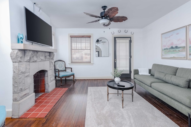 living room with baseboards, ceiling fan, a fireplace, and hardwood / wood-style flooring