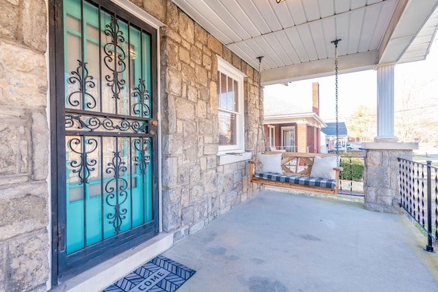 property entrance featuring stone siding and covered porch