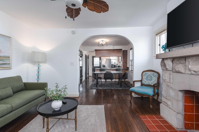 living area featuring ceiling fan, baseboards, arched walkways, and wood finished floors