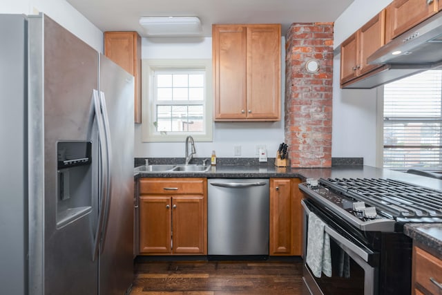 kitchen featuring a sink, dark wood-type flooring, under cabinet range hood, appliances with stainless steel finishes, and dark countertops