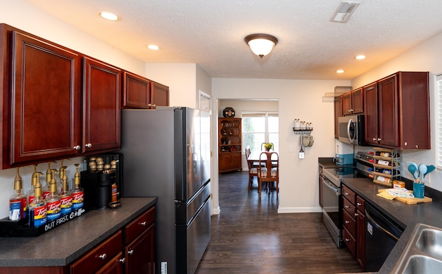 kitchen with dark countertops, stainless steel appliances, and reddish brown cabinets