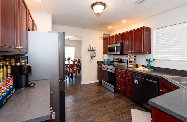 kitchen featuring dark wood-style flooring, dark brown cabinets, appliances with stainless steel finishes, a textured ceiling, and dark countertops