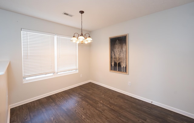 spare room with a notable chandelier, visible vents, baseboards, and dark wood-style floors