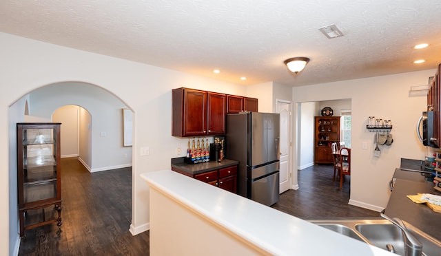 kitchen featuring recessed lighting, appliances with stainless steel finishes, dark wood-style floors, a textured ceiling, and reddish brown cabinets