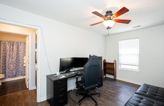 office with a ceiling fan, visible vents, dark wood-style flooring, and baseboards