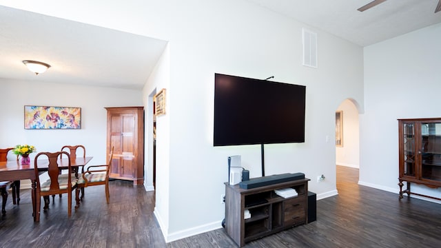 living room featuring arched walkways, visible vents, baseboards, and dark wood-style floors