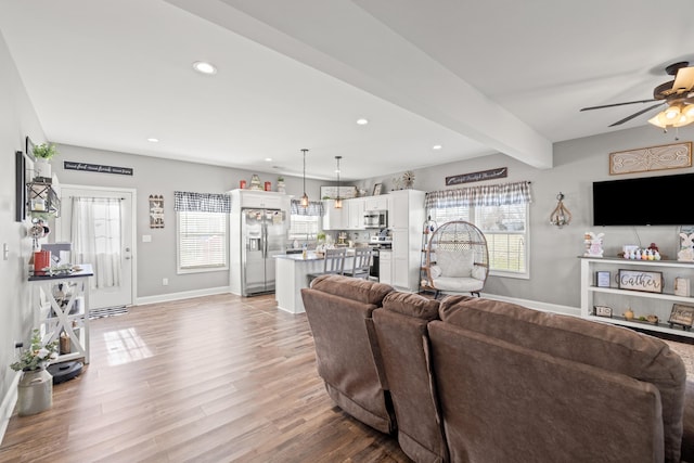 living area with recessed lighting, baseboards, beam ceiling, and light wood-style floors