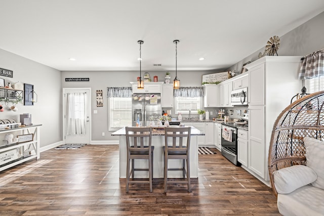 kitchen with a sink, appliances with stainless steel finishes, a center island, and dark wood-style flooring