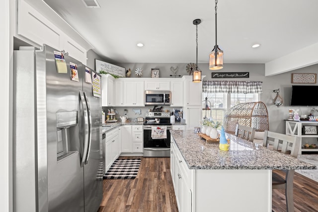 kitchen with dark wood finished floors, white cabinets, appliances with stainless steel finishes, and a kitchen island