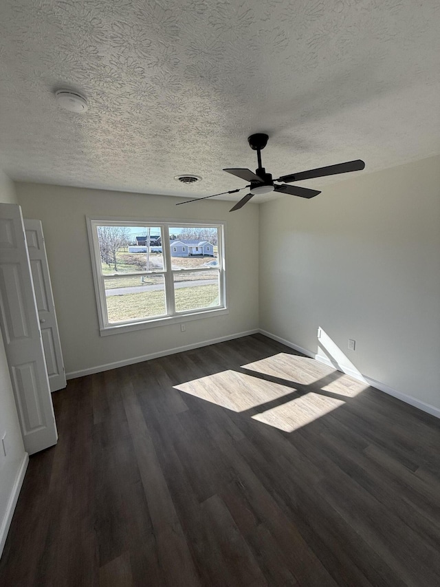 unfurnished room with a textured ceiling, dark wood-style floors, visible vents, and baseboards