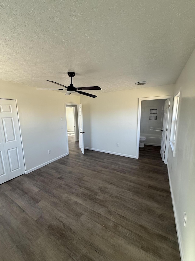 unfurnished room featuring visible vents, a textured ceiling, dark wood finished floors, baseboards, and ceiling fan