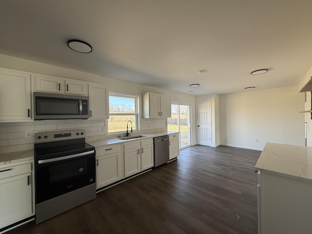 kitchen featuring dark wood-style floors, a sink, white cabinets, appliances with stainless steel finishes, and backsplash