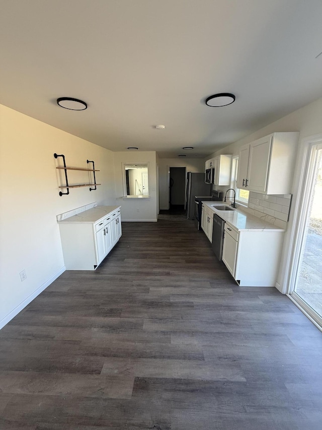 kitchen with tasteful backsplash, a sink, appliances with stainless steel finishes, white cabinetry, and dark wood-style flooring