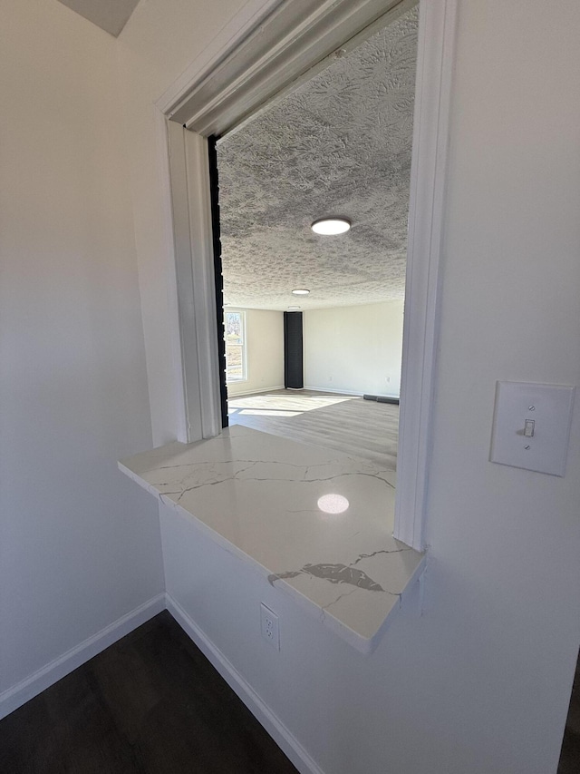 hall with baseboards, a textured ceiling, and dark wood-style floors