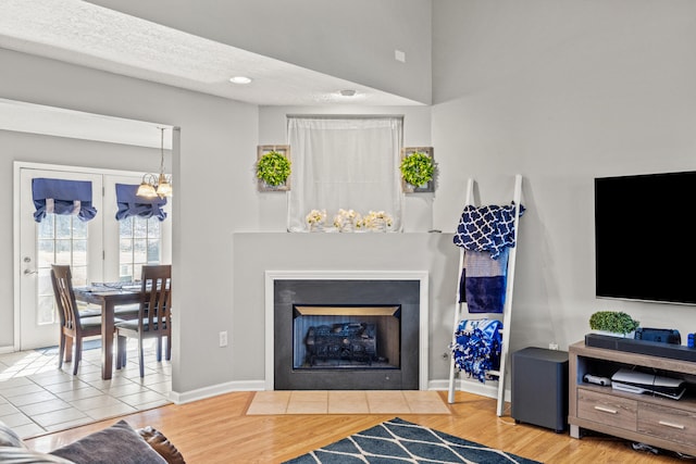 living room with baseboards, a fireplace with flush hearth, an inviting chandelier, wood finished floors, and a textured ceiling