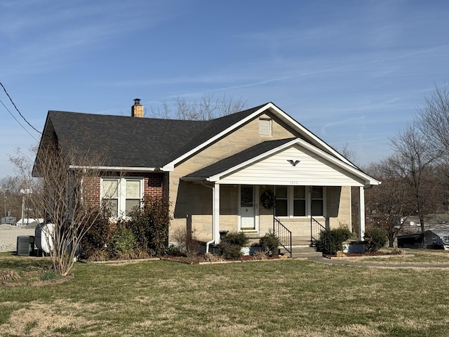 bungalow-style house with central air condition unit, a front lawn, roof with shingles, brick siding, and a chimney