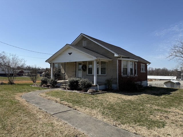 bungalow-style home featuring a front lawn, covered porch, and brick siding