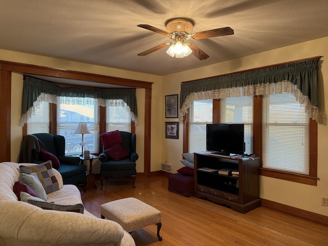 living room with light wood finished floors, visible vents, ceiling fan, and baseboards