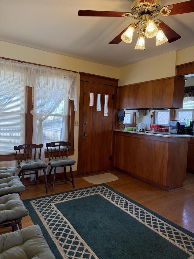 kitchen featuring a peninsula, wood finished floors, open floor plan, and brown cabinets