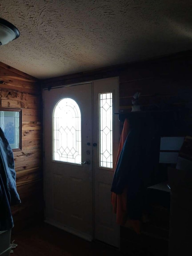 foyer entrance featuring a textured ceiling and wood walls