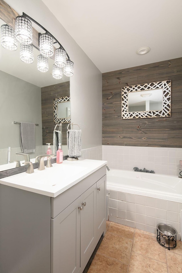 bathroom with tile patterned floors, vanity, tile walls, and a garden tub