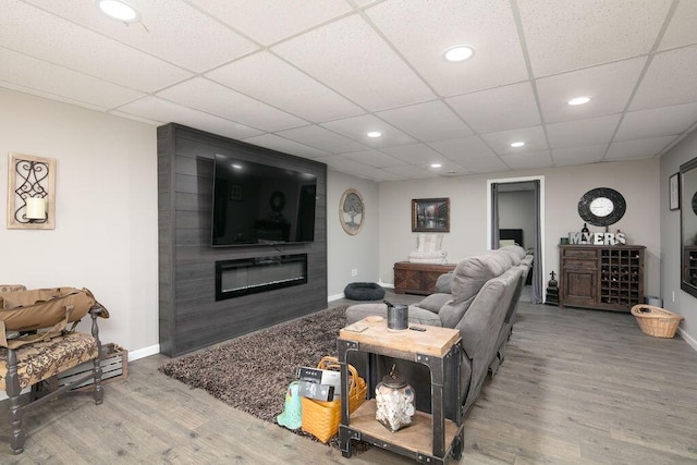 living area with a large fireplace, baseboards, recessed lighting, wood finished floors, and a paneled ceiling