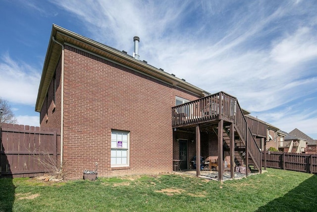 rear view of house featuring a lawn, a fenced backyard, stairway, a wooden deck, and brick siding