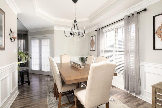 dining area with a chandelier, plenty of natural light, dark wood-type flooring, and a tray ceiling