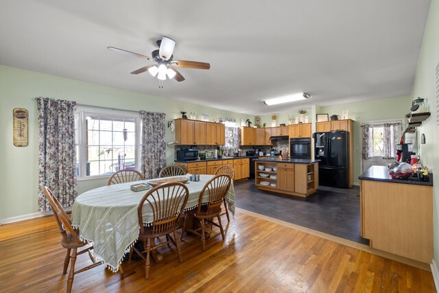 dining space with baseboards, a ceiling fan, and wood finished floors