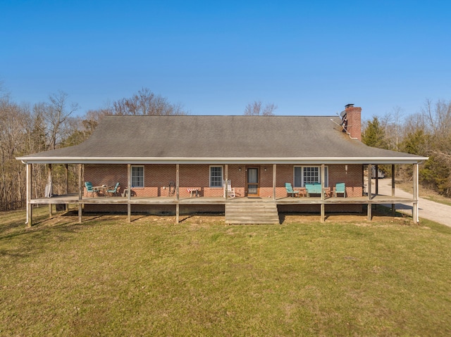 rear view of house featuring a wooden deck, a lawn, brick siding, and a chimney