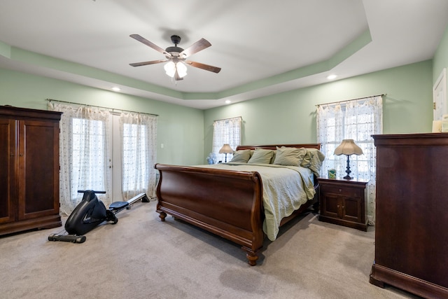 bedroom featuring light carpet, recessed lighting, a tray ceiling, and a ceiling fan