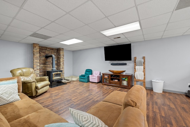 living area featuring a drop ceiling, visible vents, wood finished floors, and a wood stove