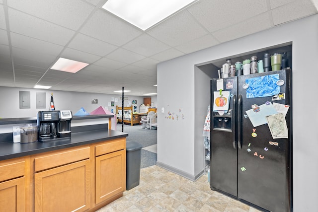 kitchen with baseboards, a paneled ceiling, dark countertops, and black refrigerator with ice dispenser