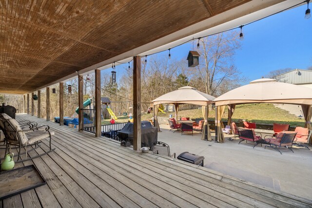 wooden terrace with a gazebo, a grill, and a playground