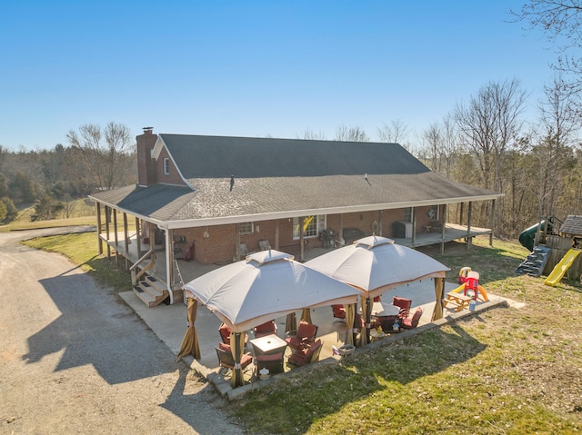 back of property with a playground, a lawn, driveway, and a chimney