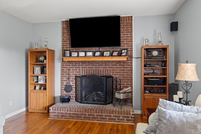 living area with baseboards, wood finished floors, and a fireplace