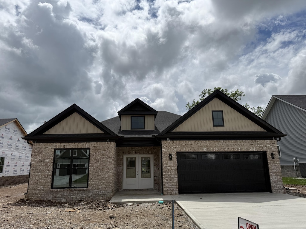 craftsman inspired home featuring a garage, french doors, brick siding, and driveway