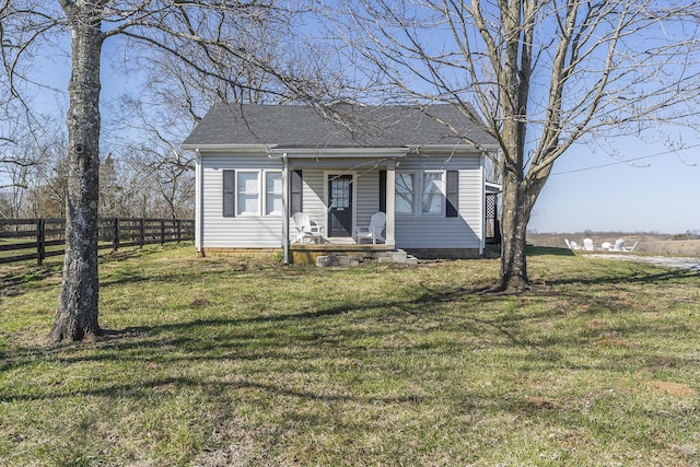 bungalow-style home with a front yard, fence, and roof with shingles