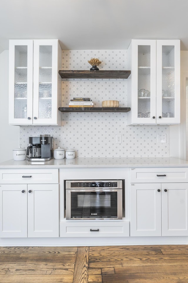 bar with oven, tasteful backsplash, and wood finished floors