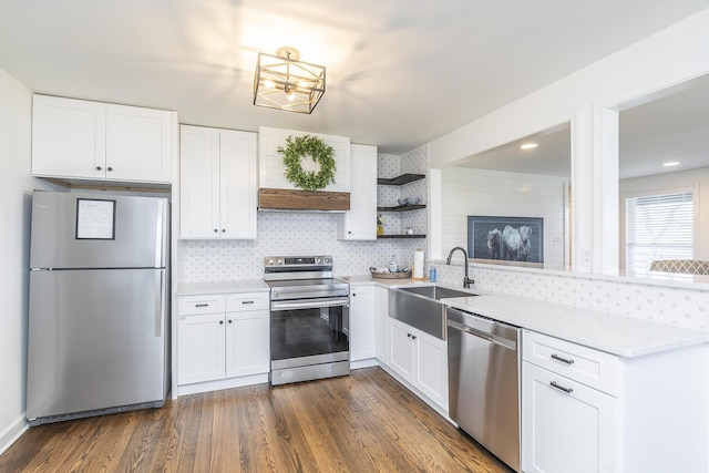 kitchen with a sink, open shelves, stainless steel appliances, a peninsula, and dark wood-style flooring